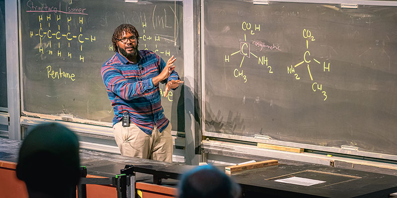 Lorenzo Lones standing in front of a blackboard teaching
